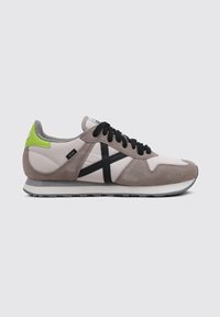 Gray and beige suede and leather sneaker with black laces, black graphic detail, and a neon green heel accent. Flat rubber sole.
