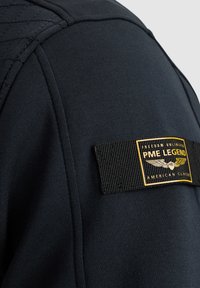 Schwarzer Sweatshirt mit einem gesteppten Schulterdesign, einem strukturierten Stoff und einem gewebten Etikett mit "PME Legend" in gelben und schwarzen Akzenten.