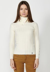 Weißer gerippter Rollkragenpullover mit umklappbarem Kragen, der Druckknopfakzente am Kragen und an den Bündchen aufweist. Enganliegendes Design.