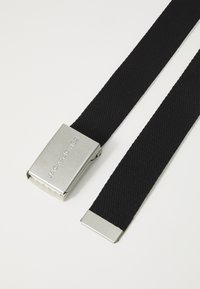 Black woven fabric belt with a silver rectangular metal buckle featuring the branding "JACK & JONES." Smooth texture, sturdy design.