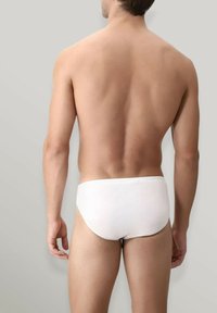 Culotte bianche in cotone con elastico in vita, viste dal retro. Il tessuto è liscio, aderente e dal design minimalista.