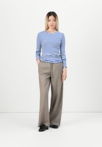 Gestreepte blouse met lange mouwen in blauw en wit, gecombineerd met beige wijde broekspijpen. Gelaagde stof met een ontspannen pasvorm, voorzien van voorzakken.
