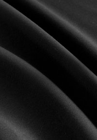Sort stof med bløde folder, der viser en glat tekstur og fin vævedetalje i nærbillede.