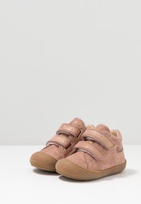 Lichtroze suède schoenen met twee klittenbandsluitingen, ronde neuzen en een geprofileerde rubberen zool. Subtiele glinsteraccenten op de bandjes.