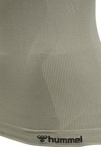 Hummel urheilu tanktoppi oliivinvihreänä, jossa on ribattu pinta, kiinteä malli ja musta logo helmassa. Pehmeä, joustava materiaali.
