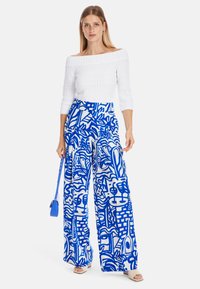 White off-the-shoulder textured top paired with blue and white patterned wide-leg pants, featuring abstract designs and loose fit.