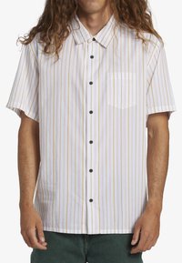Kortærmet skjorte i hvid med lodrette gule striber, med brystlomme og sorte knapper. Polyester stof, afslappet pasform.