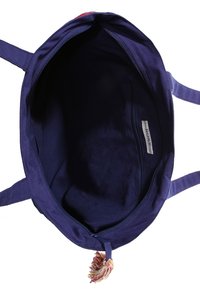 Mörkblå canvas toteväska med dragkedjestängning, med en mjuk innervägg och en färgglad kvastdetalj på dragkedjan.