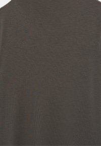 Gros plan sur une texture de tissu brun foncé uni avec un motif de tissage horizontal fin, probablement une partie d'un vêtement ou d'un textile.