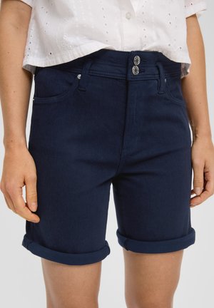 Shorts en denim bleu marine avec revers, dotés d'une fermeture à double bouton et de poches avant. Le tissu a une finition lisse, légèrement texturée.