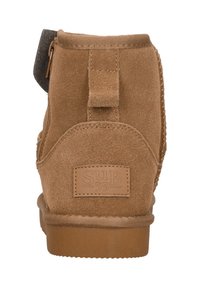 Tan kleurige suède enkellaars met een gestructureerde achterkant, voorzien van een zijrits, logo patch en een rondeneus ontwerp. Zacht materiaal met een matte afwerking.