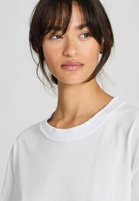 Witte katoen t-shirt met een ronde halslijn en korte mouwen, voorzien van een zachte textuur en minimale stikdetails.