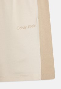 Camiseta colorblock en beige y crema de Calvin Klein, que presenta un tejido suave y texturizado con un sutil estampado de logo cerca del dobladillo.