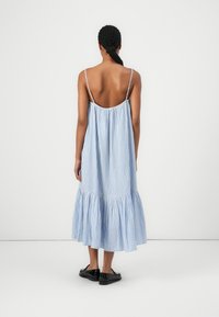 Modrá a biela pruhovaná midi šaty s vrstveným lemom, tenkými popruhmi a voľným strihom. Vyrobené z ľahkej tkaniny.