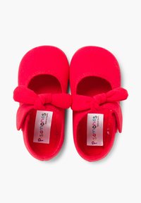 Czerwone buty Mary Jane z gładkiego materiału, okrągłym noskiem i dekoracyjną kokardą na pasku. Metki zawierają napis "Pisamonas, wyprodukowano w Hiszpanii."