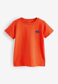 Helles orange Baumwoll-T-Shirt mit kurzen Ärmeln und Rundhalsausschnitt. Es ist mit einem kleinen, blauen und lila Lastwagen auf der linken Brust bestickt.