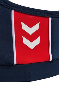 Marinblå och röd sportbehå med en strukturerad tyg, tre vita chevronmönster och en kontrasterande vit rand längs sidan.