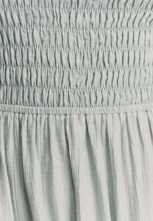 Lys blå, smocket stof med en tekstureret overflade. Har samlede sektioner med vandret strik og flydende draperinger.