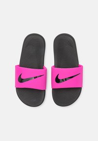 Chanclas rosa con una correa gruesa que presenta el logo negro de Nike. Suela de goma negra texturizada con surcos visibles para mayor tracción.