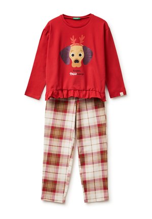 Czerwona bluzka z długim rękawem z psem noszącym poroże i napisem „Happy PAWlidays”, zestawiona z beżowymi, czerwonymi i brązowymi spodniami w kratę.