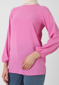 Top in cotone rosa a maniche lunghe con scollatura rotonda e polsini elasticizzati. Tessuto morbido, vestibilità comoda e orlo dritto.