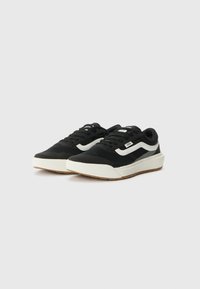 Sorte sneakers med hvitt bølgemønster, med en teksturert stoffoverdel, rundt tåparti og gummisåle med såle i gummikvalitet.