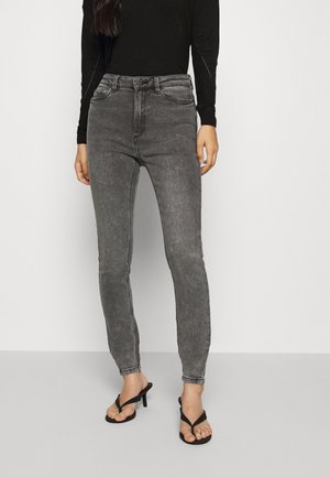 Jeans grises de talle alto con una silueta ajustada, hechos de mezclilla, con una textura suave y bolsillos frontales, combinados con chanclas negras.