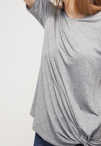 Gray short-sleeve T-shirt with draped front and knotted detail at the hem. Made from soft, lightweight fabric. Casual fit.