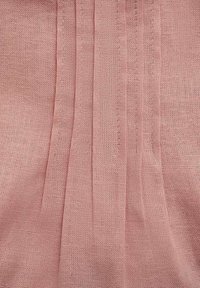 Light pink fabric with a textured, woven appearance and vertical pleats. The material is breathable and has a soft, slightly coarse texture.