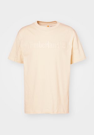 Vaaleanbeige puuvillainen t-paita, jossa on pyöreä pääntie. Paitaan on kuvattu "Timberland"-logo vaaleana kohotettuna tekstinä sekä pieni puu-symboli.