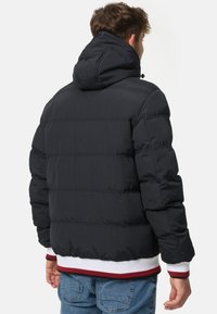 Black puffer jacket with a hood, featuring horizontal quilted sections and elasticized cuffs and hem with red and white accents.