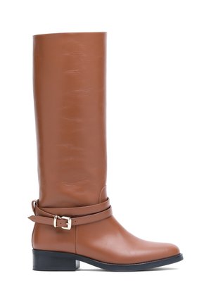 Botte haute en cuir marron avec un talon bas noir et une sangle décorative avec une boucle dorée autour de la cheville.