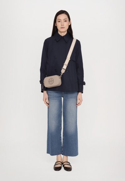 Navy double-breasted coat, light gray crossbody bag with logo, flared blue jeans, and dark brown flats. Clean, minimal design.