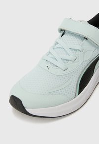 Baskets de sport bleu clair avec tige en mesh, lacets et sangle Velcro, présentant des accents noirs et une semelle en caoutchouc texturée.