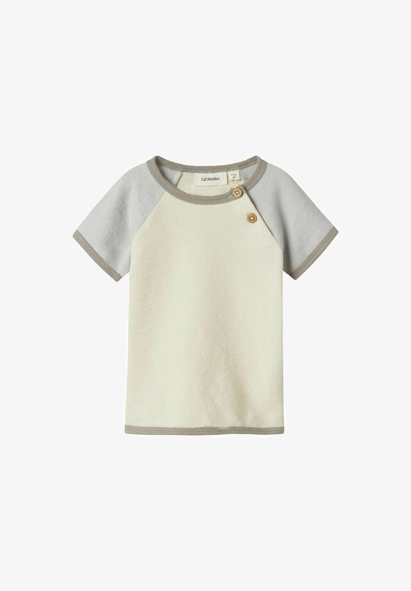 Vaalean kermansävyinen lyhythihainen paita, jossa on harmaat raglan-hihat, pyöreä kaula-aukko ja kaksi puu-nappia vasemmalla olalla. Teksturoitu kangas, jossa on kontrastiväri.