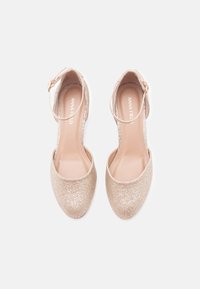 Zlaté trblietavé lodičky na vysokom podpätku s okrúhlou špičkou, pásikom okolo členku a hladkým vnútorným povrchom. Klasický štýl vhodný na formálne príležitosti.