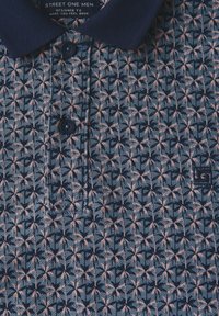 Polo de color azul marino con un patrón geométrico en rosa y azul marino, con un cuello clásico y tres botones, fabricado con una tela texturizada.