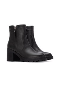 Botas negras de tobillo de cuero, con un tacón grueso, cierre de cremallera lateral y suela texturizada para mayor agarre. Parte superior lisa con detalles mínimos.