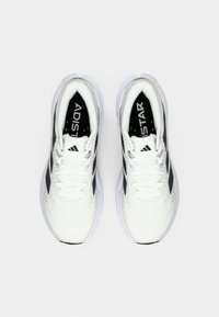 Witte sportschoenen met zwarte accenten, textuur gaas bovenkant, gevoerde zool en opvallende branding op de tong.