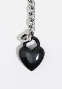 Czarny kłódka w kształcie serca wykonana z błyszczącego materiału, przymocowana do srebrnego łańcucha z okrągłymi elementami. Gładka powierzchnia, kompaktowa konstrukcja.