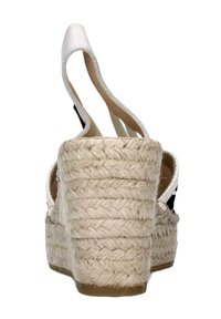 Sandalo con zeppa intrecciato beige, con cinturino alla caviglia e punta aperta, mostrato da dietro su uno sfondo bianco.