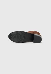 Braune Wildleder-Ankle Boots mit Gummisohle, strukturiertem Profil und niedrigem Absatz. Das Innere ist mit einem glatten Futter für zusätzlichen Komfort ausgestattet.