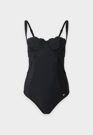 Maillot de bain une pièce noir avec détail en dentelle sur le buste et les côtés, bretelles réglables, et un petit emblème doré près de la hanche.