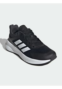 Chaussure de sport noire avec une tige en maille, design à trois rayures blanches, accents texturés noirs et semelle intermédiaire blanche rembourrée.