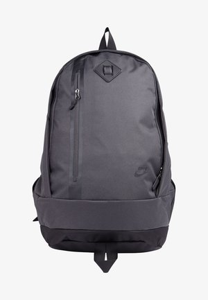 Sac à dos Nike noir avec une poche zippée verticale à l'avant, un fond rembourré et une boucle de portage supérieure.