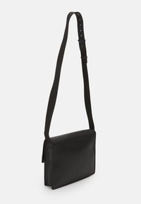 Borsa a tracolla rettangolare nera con tracolla in tessuto regolabile e chiusura a patta, mostrata su sfondo bianco.