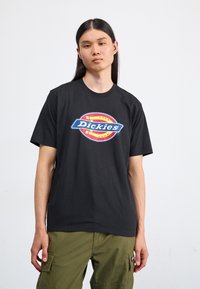 Svart bomull t-skjorte med korte ermer og en fremtredende fargerik "Dickies" logo i oval form i midten.