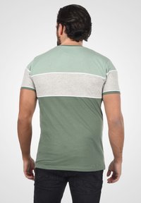 Kortærmet T-shirt i grøn og grå med et vandret farveblokdesign og kontrasterende hvid syning. Blødt bomuldsblandingsstof.