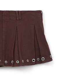 Jupe plissée marron en tissu texturé, ornée d'œillets en argent le long de l'ourlet et dotée d'une fermeture éclair au dos.