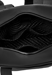 Black backpack interior with textured fabric, multiple compartments, and a patterned lining featuring the text "BE VUCH" in a repeating layout.